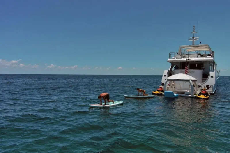 Carpe Diem Yacht Photos Pics Luxury yacht Intermarine RPH 95, 2001 model, with paddleboarders and kayakers in open sea.