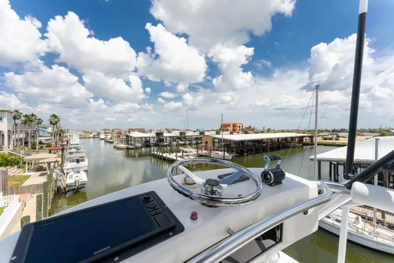 Kraken Yacht Photos Pics Helm view from 2007 Viking 52 Convertible yacht overlooking marina and cloudy sky.