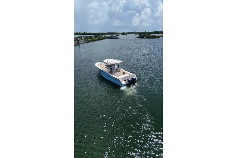  Yacht Photos Pics 2019 Grady-White Canyon 306 boat cruising on a calm waterway under a cloudy sky.