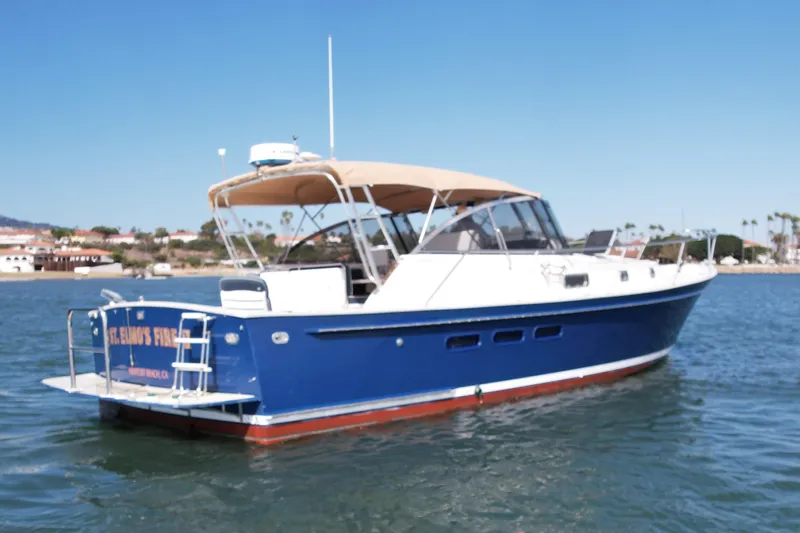 St. Elmo's Fire II Yacht Photos Pics Legacy 40 boat from 1999 on calm water, featuring a blue hull and tan canopy.