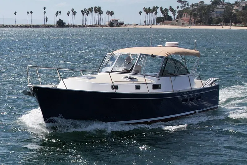 St. Elmo's Fire II Yacht Photos Pics 1999 Legacy 40 boat cruising on ocean near palm-lined shore.