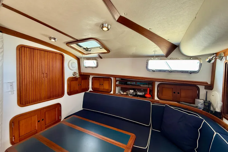 St. Elmo's Fire II Yacht Photos Pics Cozy interior of 1999 Legacy 40 sailboat with wooden cabinets and navy seating.