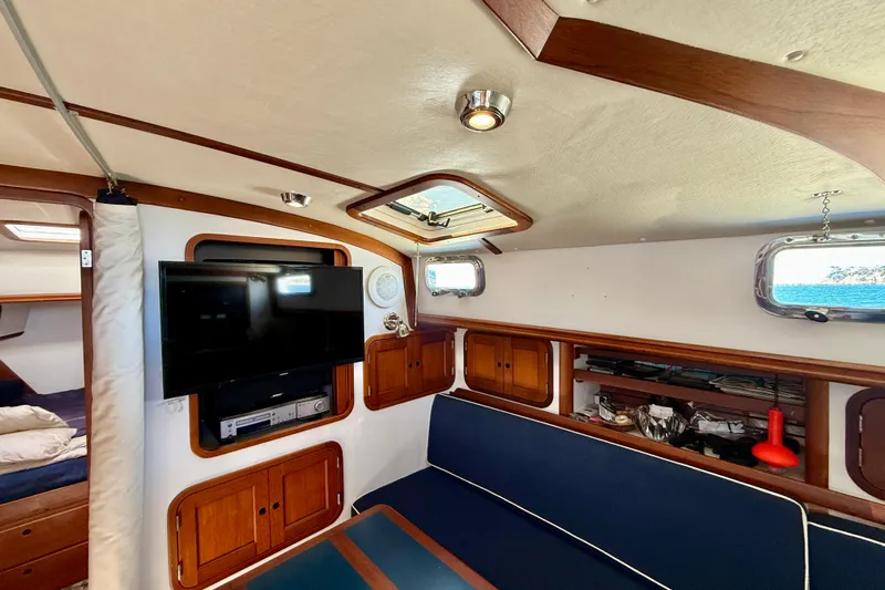 St. Elmo's Fire II Yacht Photos Pics Interior of 1999 Legacy 40 yacht with TV, blue seating, and wooden cabinets.