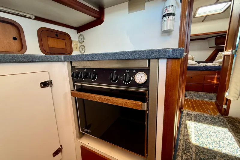 St. Elmo's Fire II Yacht Photos Pics 1999 Legacy 40 yacht interior kitchen with oven, wooden cabinetry, and cozy bedroom view.
