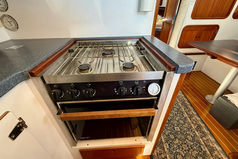 St. Elmo's Fire II Yacht Photos Pics 1999 Legacy 40 yacht kitchen with stainless steel stove and oven, wooden cabinetry, and nautical decor.