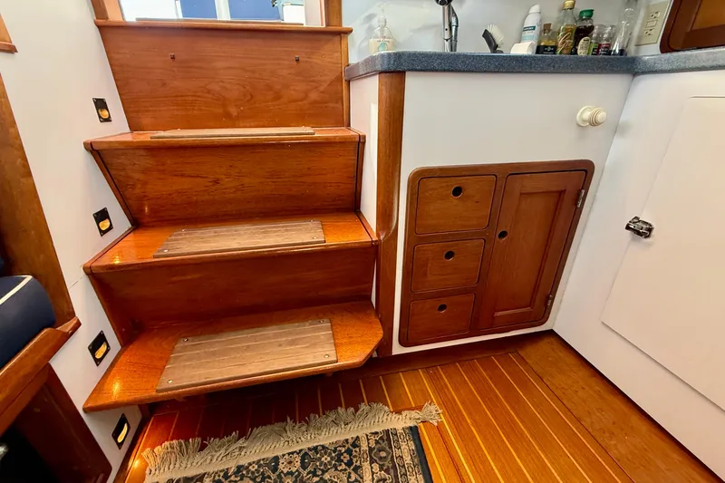 St. Elmo's Fire II Yacht Photos Pics Wooden stairs and cabinetry inside a 1999 Legacy 40 boat, featuring a small kitchenette.