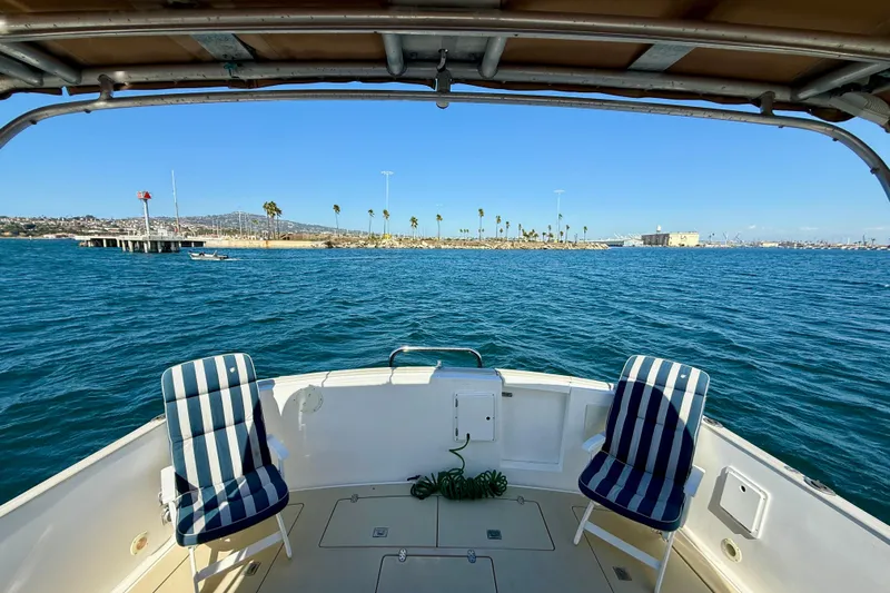 St. Elmo's Fire II Yacht Photos Pics Boat deck view with striped chairs, overlooking calm blue water and distant shoreline. Legacy 40, 1999.