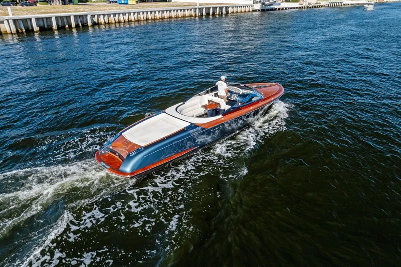 Isola Yacht Photos Pics 2013 Riva 33 Aquariva luxury boat cruising on a serene waterway.