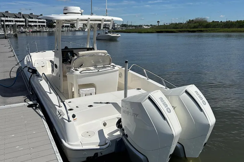 Bae Life Yacht Photos Pics 2022 Boston Whaler 270 Dauntless boat docked by the water, featuring dual outboard engines.