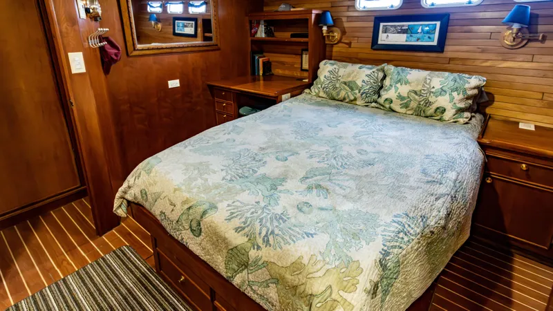  Yacht Photos Pics Cozy bedroom in 2002 Kristen Yachts Pilothouse Explorer 52 with wooden interior and floral bedding.