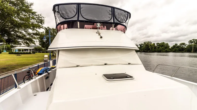  Yacht Photos Pics 2002 Kristen Yachts Pilothouse Explorer 52 docked by a scenic riverside.