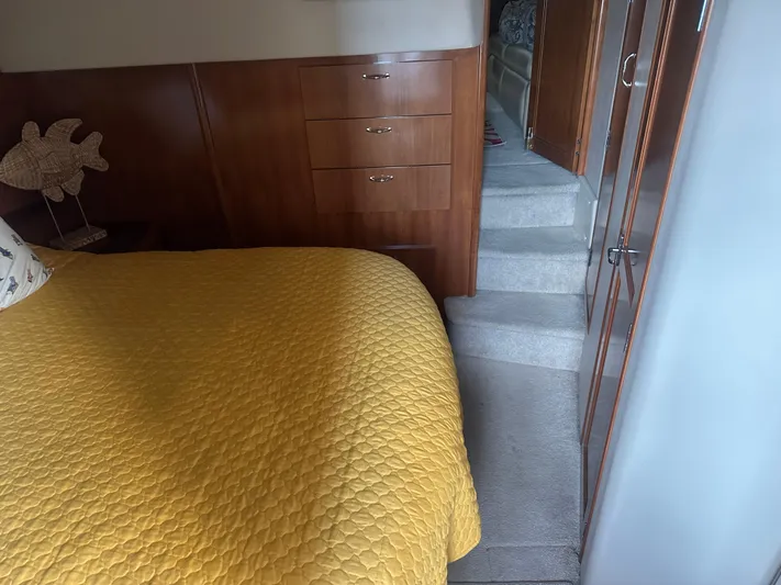  Yacht Photos Pics Interior of 2005 Carver 44 CMY with yellow bedspread, wooden cabinets, and carpeted stairs.