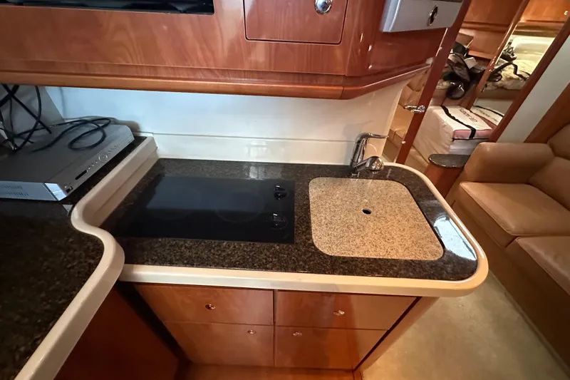  Yacht Photos Pics 2006 Four Winns 378 Vista yacht kitchen with stove and sink, featuring wood cabinetry.