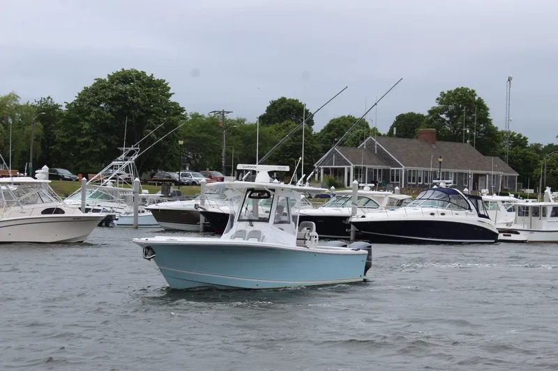 Dojo Yacht Photos Pics 2020 Regulator 28 boat navigating marina with other vessels and waterfront building.