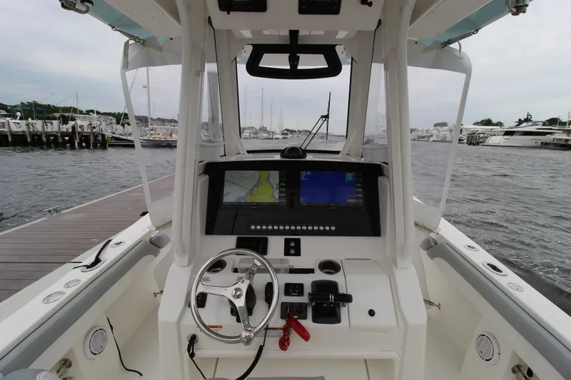 Dojo Yacht Photos Pics 2020 Regulator 28 boat cockpit with navigation screens and steering wheel at dock.
