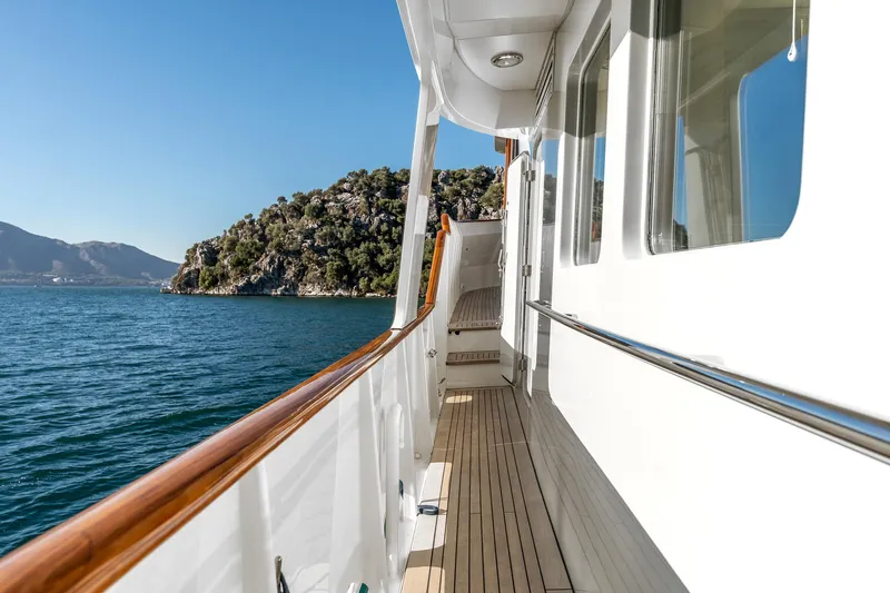Yosma Yacht Photos Pics Side deck of a 2013 71' motor yacht cruising near a scenic coastline.