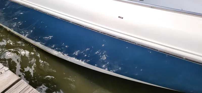  Yacht Photos Pics 2004 Boston Whaler 320 Outrage boat hull reflecting sunlight on water.