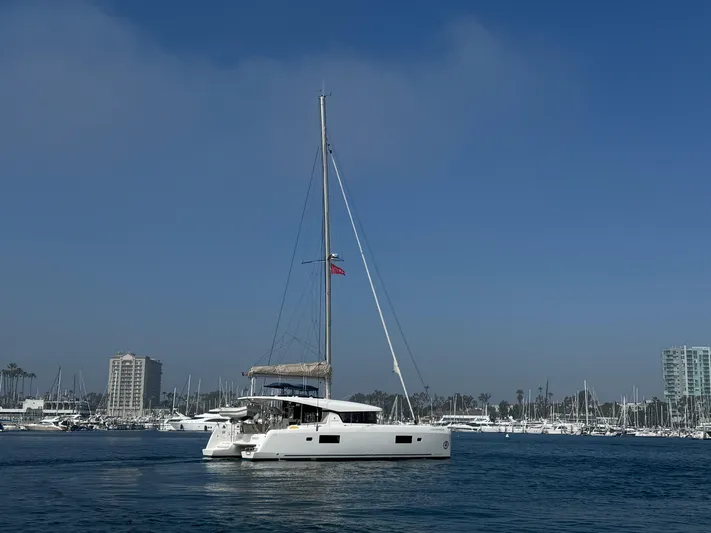 Catalina Breeze Yacht Photos Pics 2022 Lagoon 42 catamaran sailing in a marina with clear blue skies.