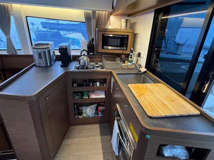 Catalina Breeze Yacht Photos Pics Modern kitchen interior of 2022 Lagoon 42 yacht with appliances and wooden cabinetry.