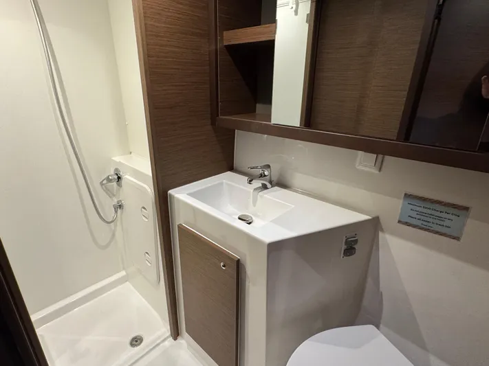 Catalina Breeze Yacht Photos Pics Modern bathroom in 2022 Lagoon 42 yacht with shower, sink, and wooden cabinetry.