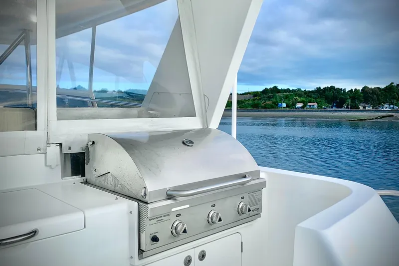 Bravo! Yacht Photos Pics Outdoor grill on 2012 Outer Reef Yachts 700 Motoryacht, overlooking serene water and lush shoreline.