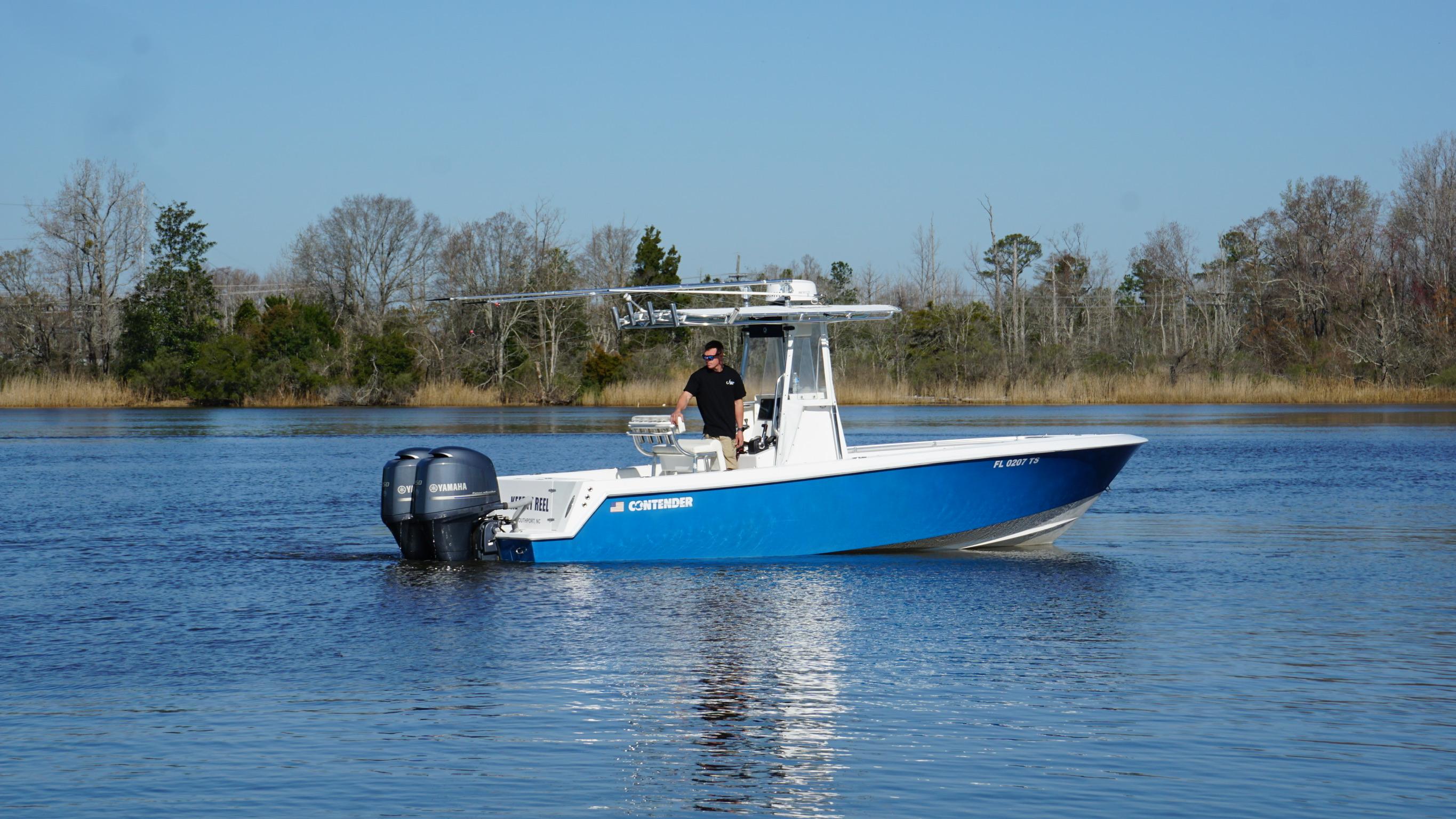 2015 Contender 25 Tournament boat on calm water, featuring dual outboard engines.