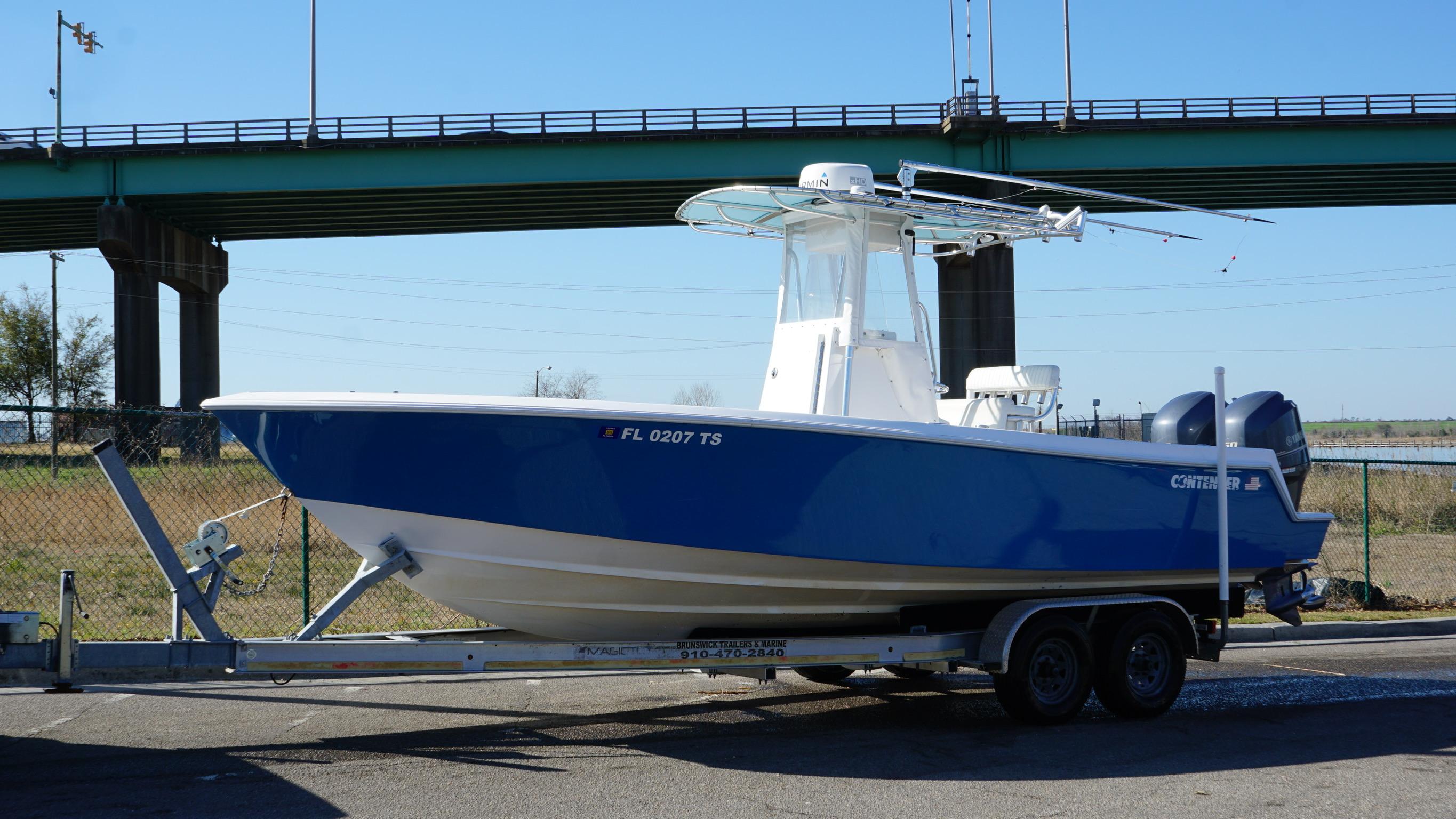 2015 Contender 25 Tournament boat on trailer, parked near a bridge.