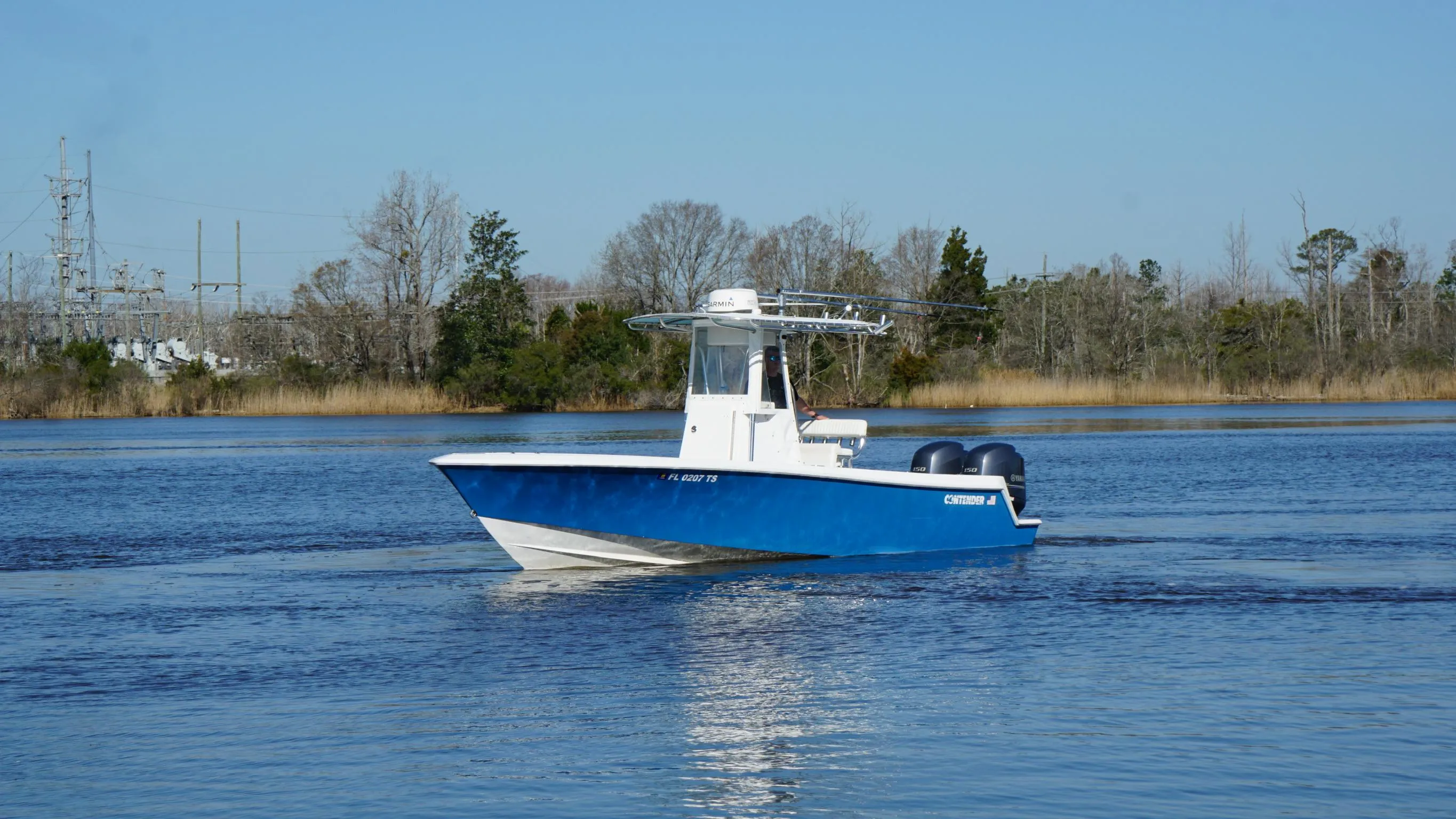 2015 Contender 25 Tournament boat on calm water, blue hull, twin engines, clear sky.