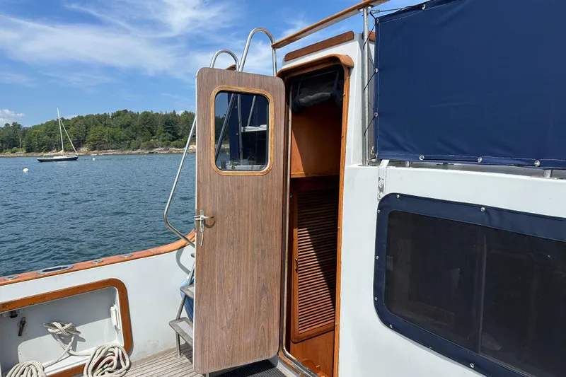  Yacht Photos Pics 1987 Albin North Sea Trawler with open cabin door, docked near scenic shoreline.