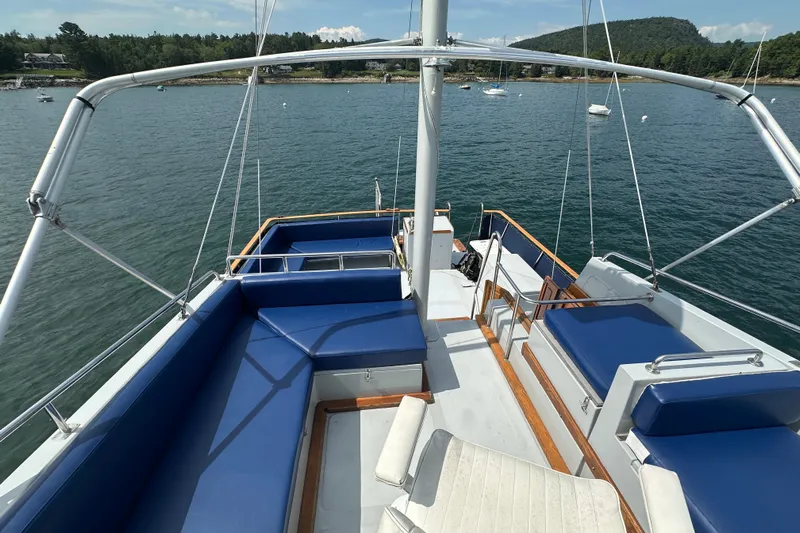  Yacht Photos Pics 1987 Albin North Sea Trawler with blue seating, docked in a scenic bay.