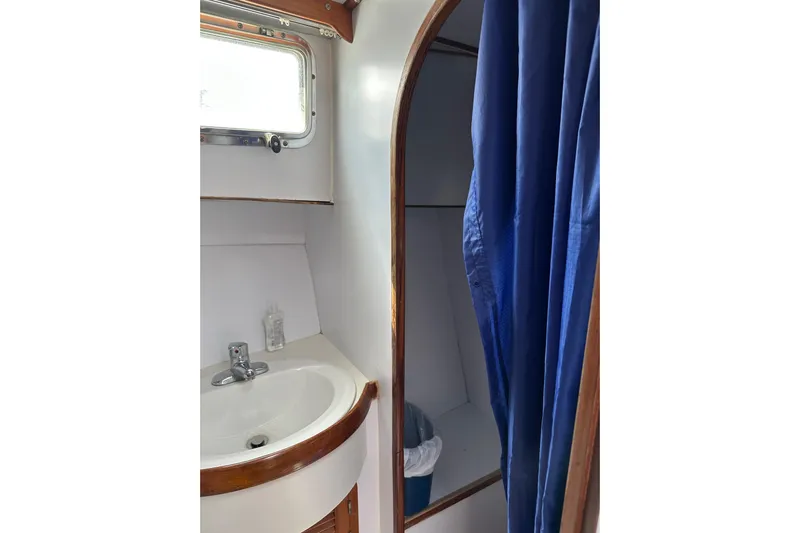  Yacht Photos Pics 1987 Albin North Sea Trawler bathroom with sink, window, and blue shower curtain.