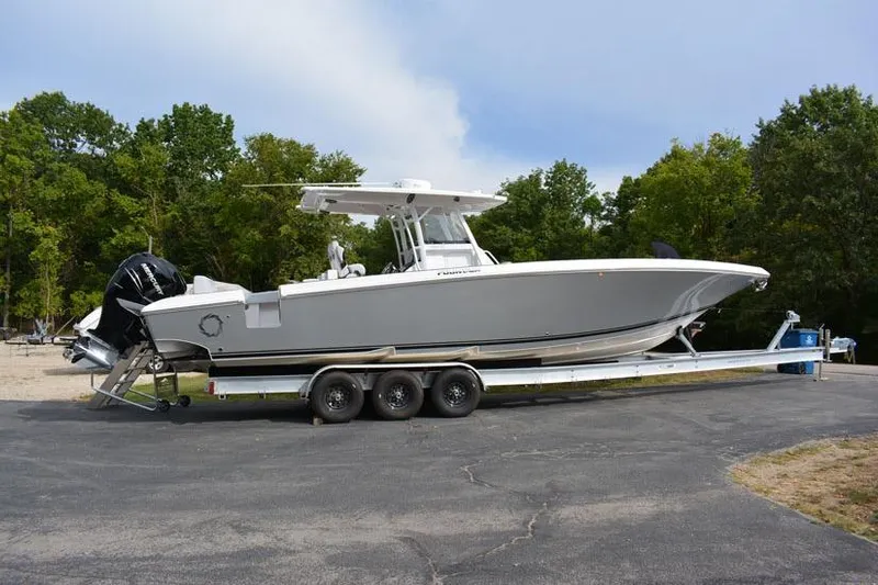  Yacht Photos Pics 2018 Fountain 38 CC boat on trailer, parked outdoors with trees in background.