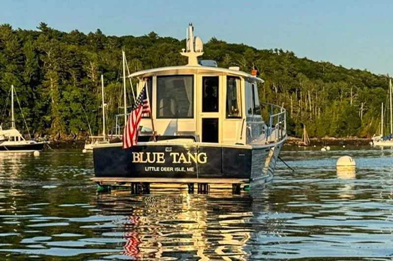 Blue Tang Yacht Photos Pics 2007 Grand Banks 39 Eastbay SX boat named "Blue Tang" on calm water near forested shore.