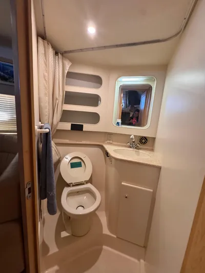  Yacht Photos Pics 1998 Carver 405 Aft Cabin bathroom with toilet, sink, mirror, and storage shelves.