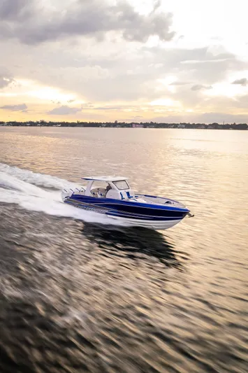  Yacht Photos Pics 2024 Deep Impact 399 Sport boat cruising on calm water at sunset.