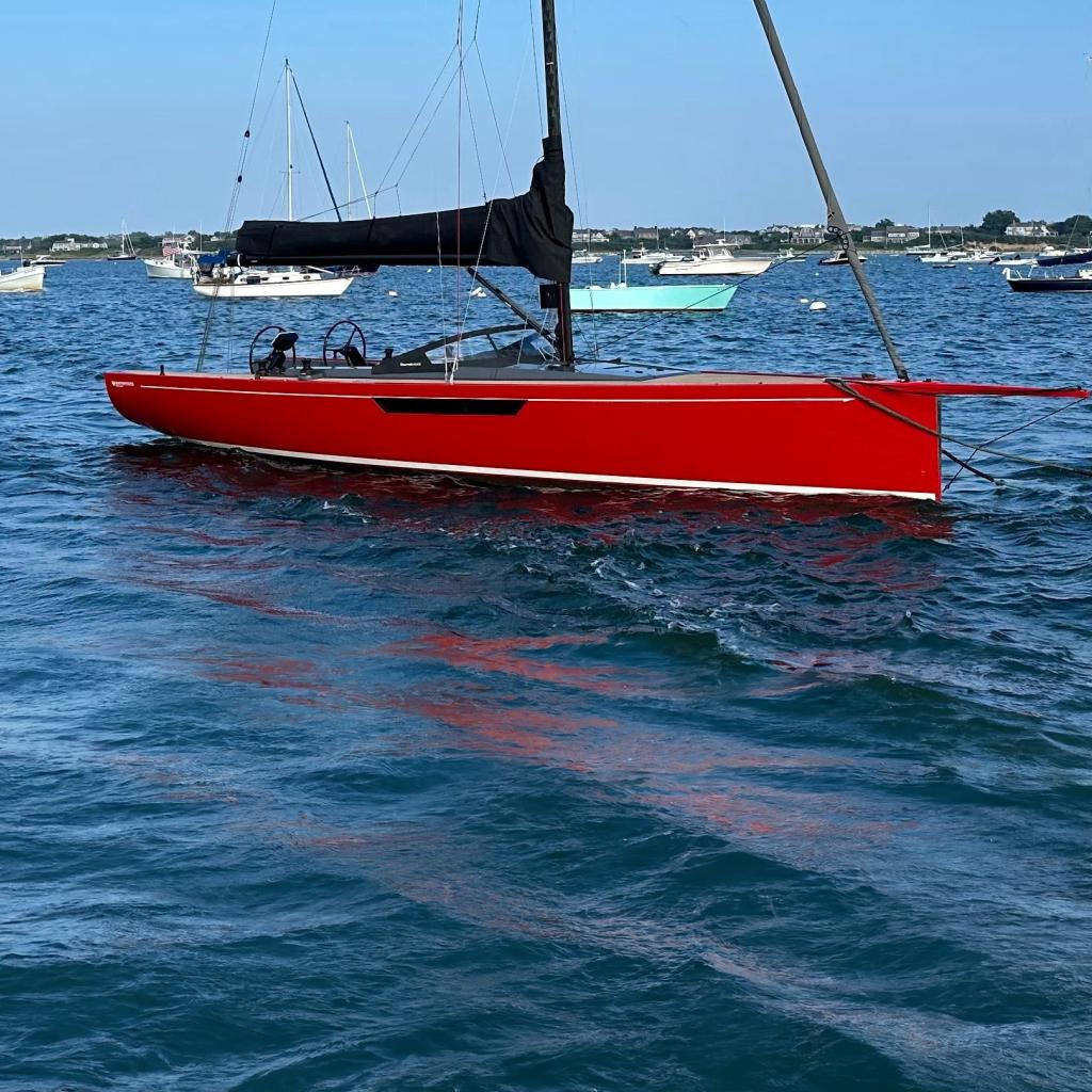 Red 2023 Saffier 33 Life sailboat on calm blue water under clear sky.