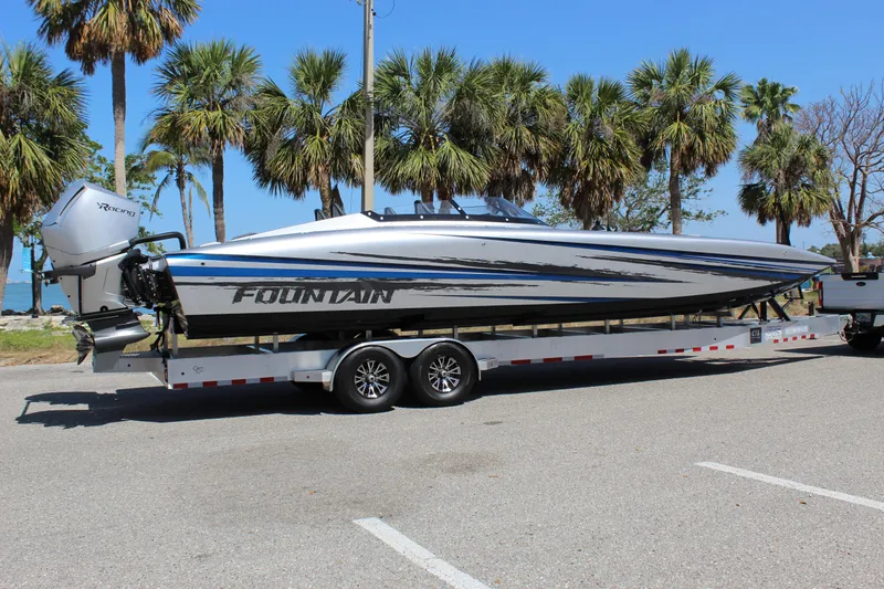  Yacht Photos Pics 2025 Fountain 34 Thundercat boat on trailer, parked near palm trees under clear blue sky.