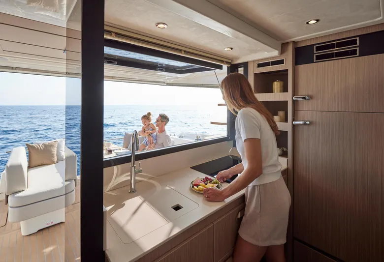  Yacht Photos Pics Woman preparing food in Prestige F 4.9 yacht kitchen, ocean view, 2025 model.