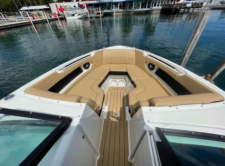  Yacht Photos Pics 2022 Sea Ray SLX 280 boat interior with tan seating and wood flooring at a marina.