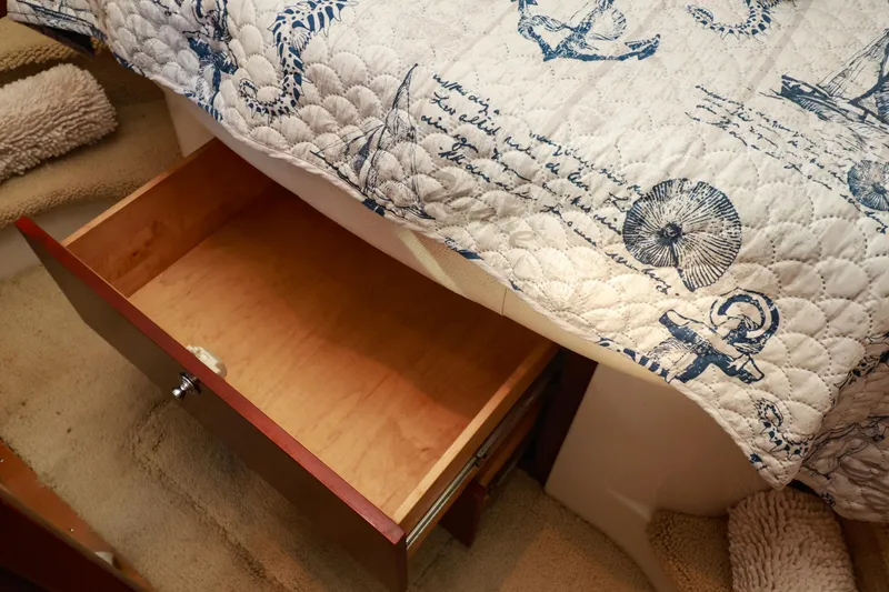Aphrodite Yacht Photos Pics Open wooden drawer under nautical-themed quilt on Chris-Craft Roamer 40, 2004 model.