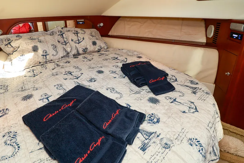 Aphrodite Yacht Photos Pics Luxurious 2004 Chris-Craft Roamer 40 cabin with nautical-themed bedding and branded towels.