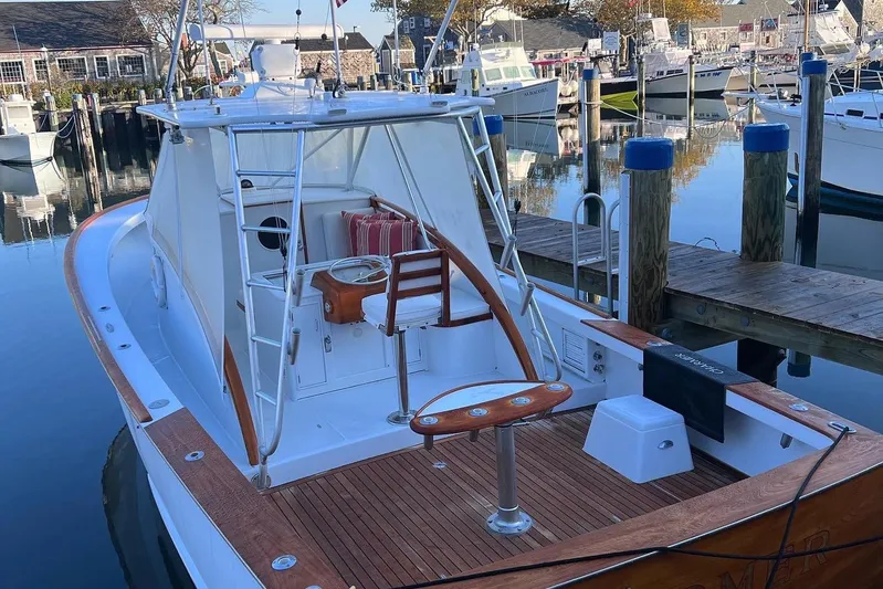 Charmer Yacht Photos Pics 1985 Rybovich Walkaround boat docked at a marina, featuring a wooden deck and fishing chair.