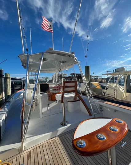 Charmer Yacht Photos Pics 1985 Rybovich Walkaround boat with American flag, docked under clear blue sky.