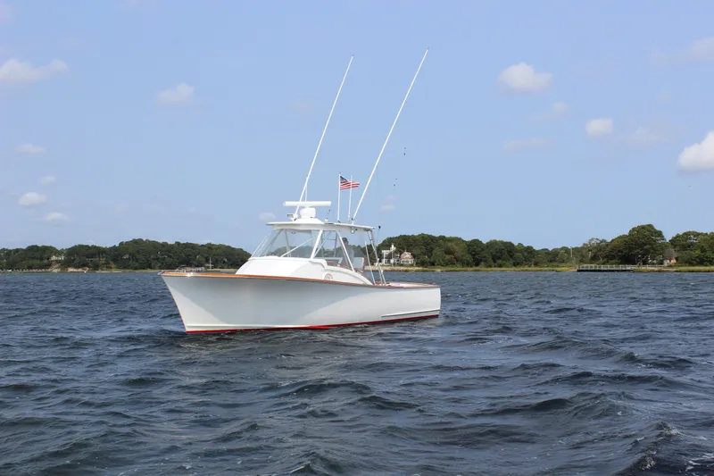 Charmer Yacht Photos Pics 1985 Rybovich Walkaround boat on calm waters with a scenic shoreline background.