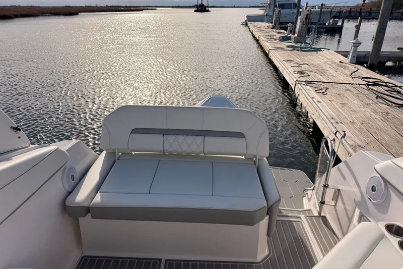  Yacht Photos Pics 2022 Regal 26 XO boat with white seating, docked by a serene waterfront.