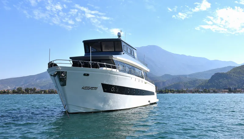  Yacht Photos Pics 2024 Custom Modern Trawler RPH yacht on serene water with mountainous backdrop.