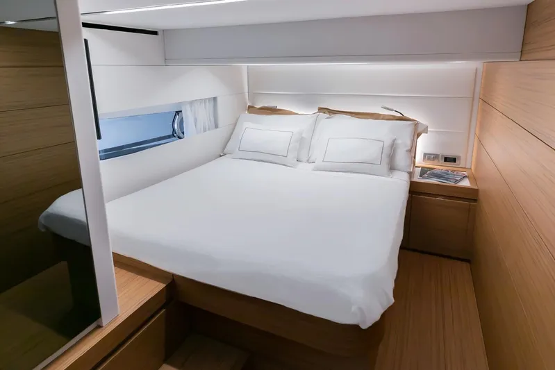  Yacht Photos Pics Luxurious bedroom interior of 2026 Solaris Power 52 Coupe yacht, featuring modern design and cozy bedding.