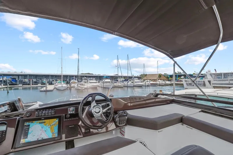 Good Vibes Yacht Photos Pics 2022 Galeon 470 Sky yacht helm with marina view, featuring navigation display and steering wheel.