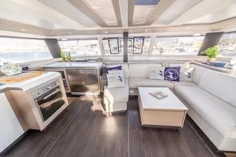 Spirit Of Ecstacy Yacht Photos Pics Luxurious interior of 2023 Fountaine Pajot Tanna 47 yacht with modern kitchen and seating area.