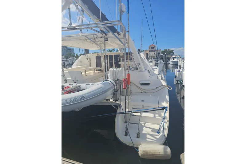 Beshert Yacht Photos Pics 2004 Leopard 47 catamaran docked at marina, featuring inflatable dinghy and clear blue sky.